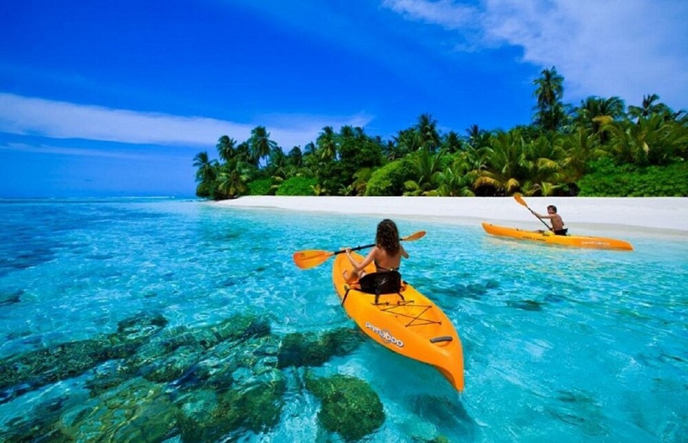 International tourists enjoying SUP boarding on the calm turquoise lagoon as a relaxing activity while staying at Corona Casino Phu Quoc