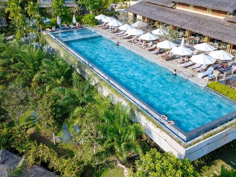 Luxury travelers relaxing by the lush green infinity pool at Lahana Resort Phu Quoc near the world-class Corona Casino Phu Quoc complex