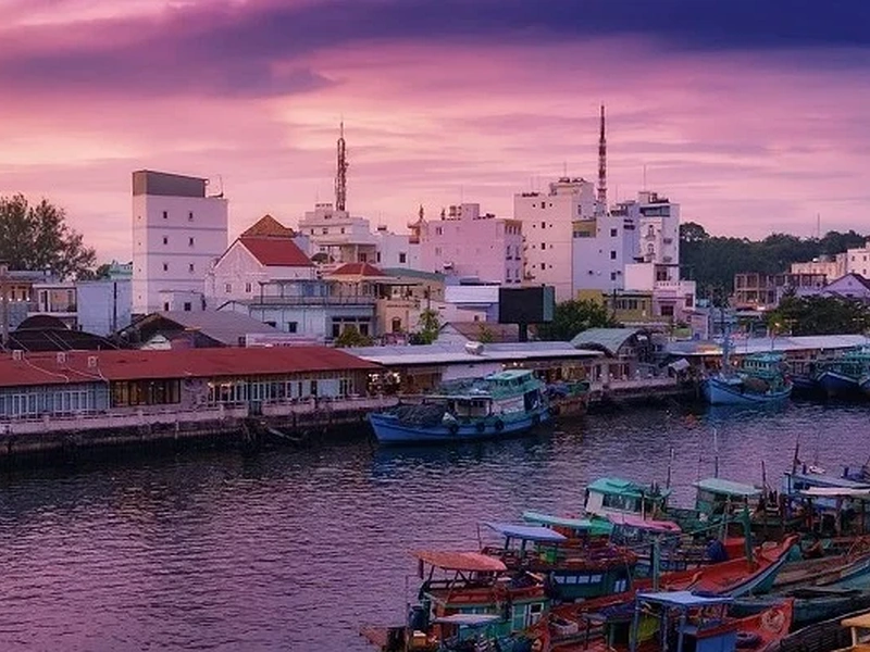 Waterfront city at sunset with colorful fishing boats near Corona Resort & Casino Phu Quoc