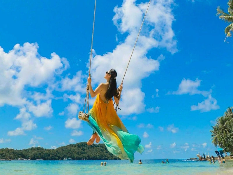 A woman enjoying a swing at a tropical beach on a Phu Quoc 5 day itinerary near Corona Resort & Casino Phu Quoc