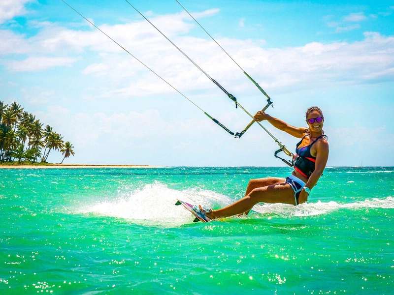 A smiling woman kitesurfing close to palm-fringed shores near Corona Resort & Casino Phu Quoc